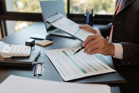 a businessman is reviewing accounting and financial statistics documents in his private office, the...