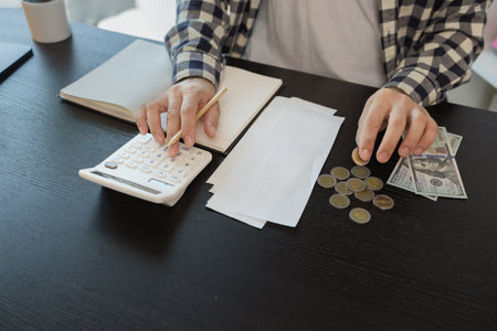 he is calculating the amount of money from all his income to allocate to various monthly expenses, the monthly invoices are sent when the payment is due, saving, money, earningの写真素材
