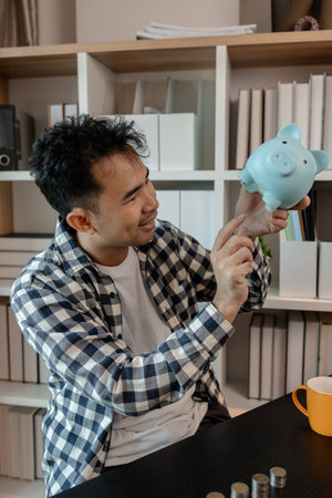he is saving money for his future plans, putting some if his income in a piggy bank, he is saving bills and coins for emergencies, the coins are stacked on top of each other, earningの写真素材