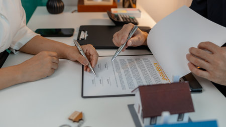 staff is explaining the information about the house lease contract documents to the buyer, the buyer signs the house lease agreement acknowledgment contract with the staff to transfer the ownershipの写真素材