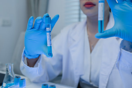 a female scientist is working in lab, a chemist tests liquid sample in science laboratory, she wears a lab coat when she works in laboratory, test tube, scientific equipmentの写真素材