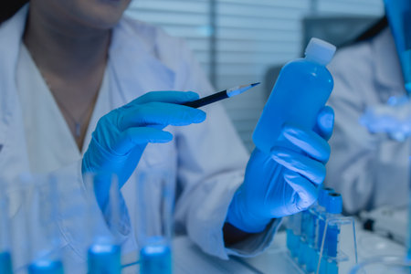 a female chemist is testing various liquid compounds in a lab, a scientist is doing research on the development, she wears a lab coat when she works in laboratory, test tube, scientific equipmentの写真素材