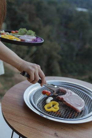 People cooking on a grill, grilling meat on an outdoor grill, grilling and cooking on a holiday with family having an outdoor BBQ party.の写真素材