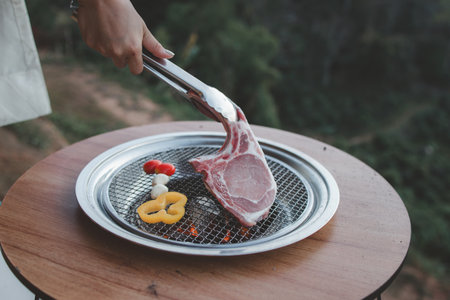 People cooking on a grill, grilling meat on an outdoor grill, grilling and cooking on a holiday with family having an outdoor BBQ party.の写真素材