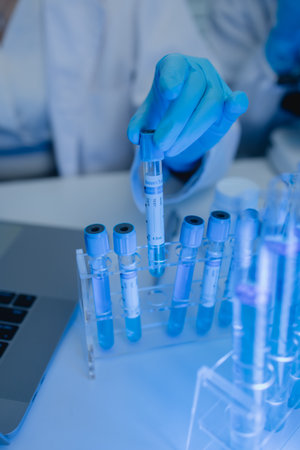 a female chemist is testing various liquid compounds in a lab, a scientist is doing research on the development, she wears a lab coat when she works in laboratory, test tube, scientific equipmentの写真素材