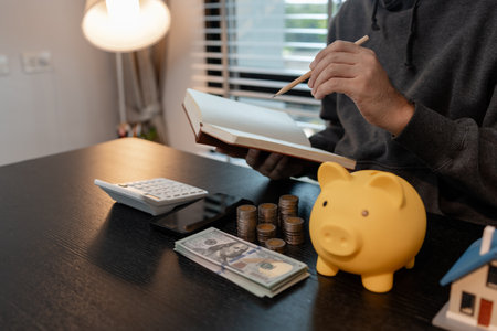 a man is calculating the money from his savings account to buy a house, this man is calculating his finances to plan for buying a house, financial, calculate, income, investmentの写真素材