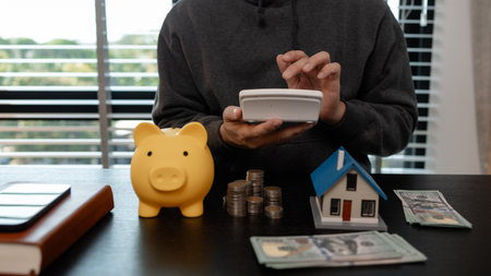 a man is calculating the money from his savings account to buy a house, this man is calculating his finances to plan for buying a house, financial, calculate, income, investmentの写真素材