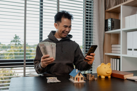 a man uses his savings to buy his dream home, this man plans his finances to buy a home, he uses his savings to buy a home as an investment, financial, money, property, paymentの写真素材