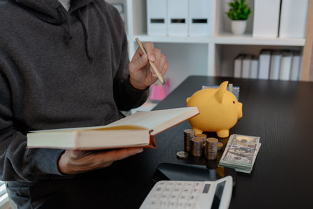 a man is calculating the money from his savings account to buy a house, this man is calculating his finances to plan for buying a house, financial, calculate, income, investmentの写真素材