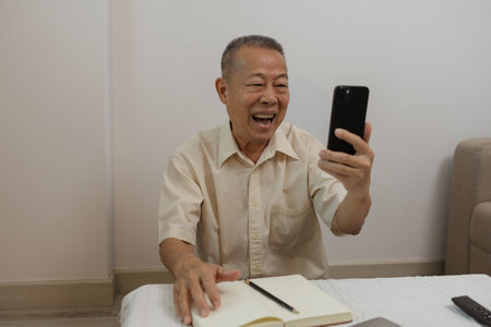 a father spends his retirement years comfortably in his home, a grandfather spends his free time during the day doing various activities in the living roomの写真素材