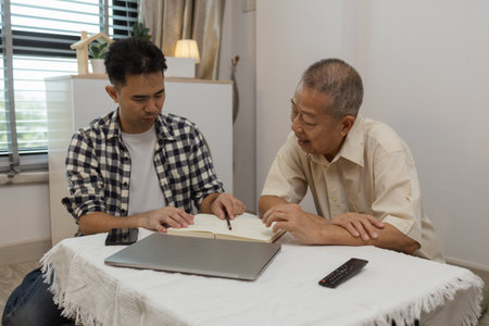 a father and son are spending their free time together at home, the son spends his weekend visiting his elderly father, a family full of love between a father and sonの写真素材