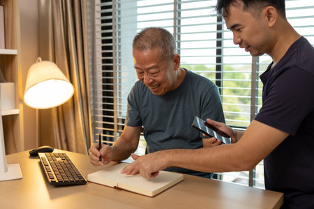 a father and son are spending their free time together at home, the son spends his weekend visiting his elderly father, a family full of love between a father and sonの写真素材
