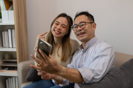 a father and daughter are spending their free time together at home, the daughter spends her weekend visiting her elderly father, a family full of love between a father and daughterの写真素材