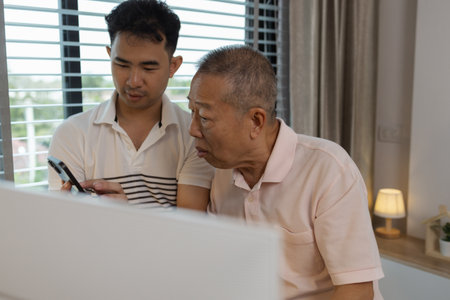 a father and son are spending their free time together at home, the son spends his weekend visiting his elderly father, a family full of love between a father and sonの写真素材