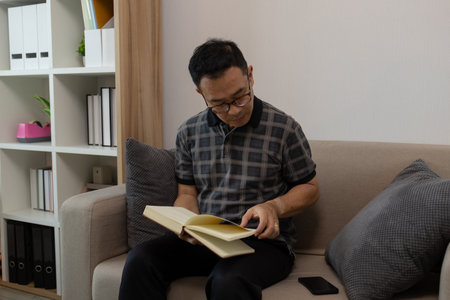 a father spends his retirement years comfortably in his home, a grandfather spends his free time during the day doing various activities in the living roomの写真素材