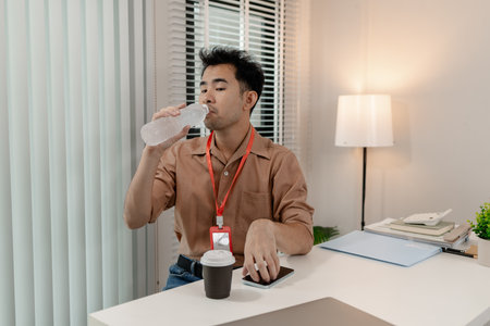 this businessman is relaxing in his office after long day work with his phone, he is spent his free time on his phone in the office, relax, head of marketing feel relax in his office with his phoneの写真素材