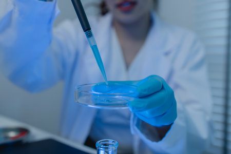 a female scientist is working in lab, a chemist tests liquid sample in science laboratory, she wears...