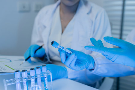 two scientists consult each other while conducting an experiment on a liquid substance in a...