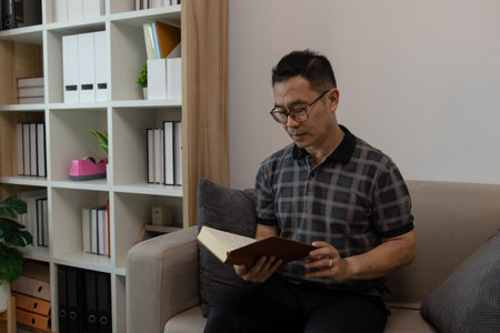 a father spends his retirement years comfortably in his home, a grandfather spends his free time during the day doing various activities in the living roomの写真素材