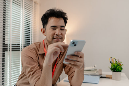 this businessman is relaxing in his office after long day work with his phone, he is spent his free time on his phone in the office, relax, head of marketing feel relax in his office with his phoneの写真素材