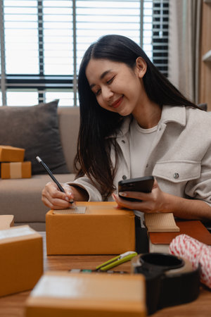 an entrepreneur is packing parcel for order from customer, she own a small business, sme, a lot of...