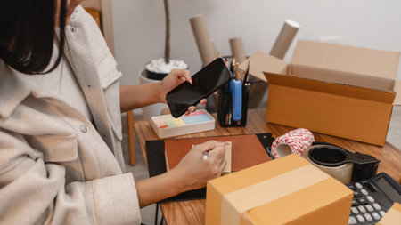 an entrepreneur is packing parcel for order from customer, she own a small business, sme, a lot of package in the room, e-business is running by a this entrepreneur, online shoppingの写真素材