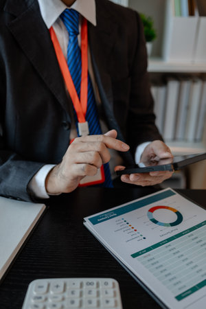 a businessman woks with a foreign company and uses a smartphone to help send and receive information, marketing manager sends statistic information to accounting department via a smartphoneの写真素材