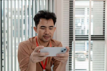 this businessman is relaxing in his office after long day work with his phone, he is spending his free time on his phone in the office, relax, head of marketing feels relax in his office with his phoneの写真素材