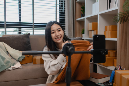 she live to sell her product online, sme, she is an entrepreneur and own a small business, live streaming, parcel, she is selling her product online, talking to customer when she liveの写真素材
