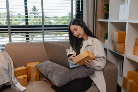 this businesswoman own a small business, sme, she is working in online business to sell her product, a lot of parcel, package, an entrepreneur is working on the parcel before deliver to customerの写真素材