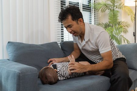 A tender moment of a father holding his baby, as the infant looks up with curiosity and trust. The...