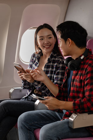 A young couple enjoys their travel experience together, smiling and chatting while sitting in...