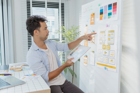 A young designer is working on a UX UI project, analyzing mobile app wireframes and choosing color...