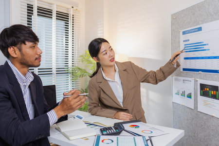 Business colleagues are actively engaged in a collaborative meeting, reviewing charts, pointing at data, and exchanging ideas. Their teamwork reflects strategy planning, analysis, and cooperation.の写真素材