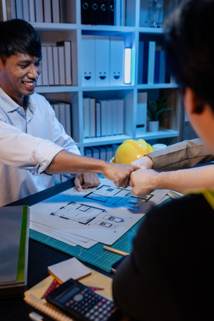 A group of engineers and architects collaborate on a construction project, discussing ideas and sharing technical plans to design innovative modern buildings in a creative teamwork environment.の写真素材