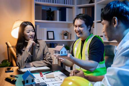 Architects and engineers work together in an office to review blueprints, exchange ideas, and refine their building plans for a contemporary construction project in an urban setting.の写真素材