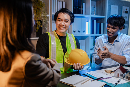 Architects and engineers work together in an office to review blueprints, exchange ideas, and refine their building plans for a contemporary construction project in an urban setting.の写真素材
