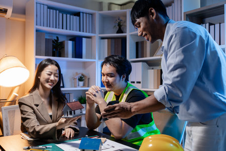 Architects and engineers work together in an office to review blueprints, exchange ideas, and refine...