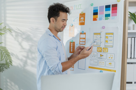 A designer is developing UX UI layouts, reviewing mobile app prototypes, and arranging interface...
