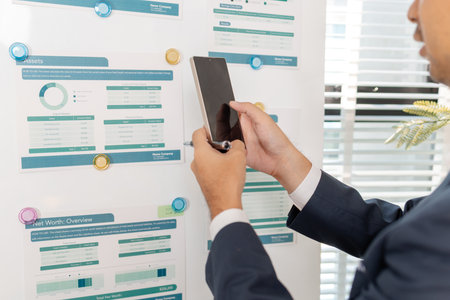 A business analyst examining charts and statistics on a whiteboard, using data-driven insights to...
