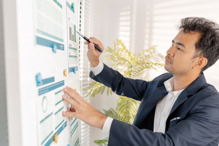 A businessman preparing a marketing and financial plan in a modern office, reviewing charts and data...