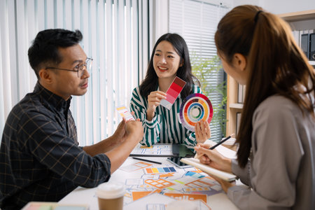 A group of UX/UI designers brainstorming creative ideas together, discussing color palettes and layout concepts for a new mobile application interface in a modern design office.の写真素材