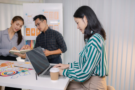 UX/UI designers collaborating during a creative workshop to test interface ideas and exchange feedback for app development, emphasizing teamwork and innovative design thinking.の写真素材