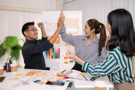 UX/UI designers collaborating during a creative workshop to test interface ideas and exchange feedback for app development, emphasizing teamwork and innovative design thinking.の写真素材