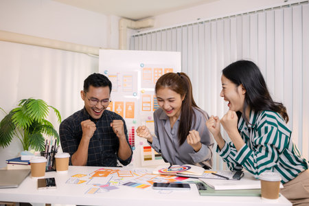 UX/UI designers collaborating during a creative workshop to test interface ideas and exchange feedback for app development, emphasizing teamwork and innovative design thinking.の写真素材