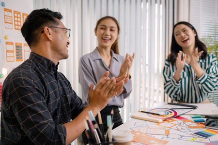 UX/UI designers collaborating during a creative workshop to test interface ideas and exchange feedback for app development, emphasizing teamwork and innovative design thinking.の写真素材