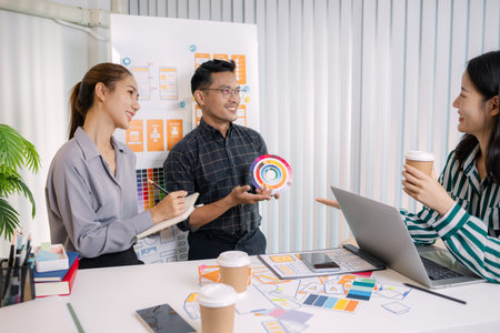 UX/UI designers collaborating during a creative workshop to test interface ideas and exchange feedback for app development, emphasizing teamwork and innovative design thinking.の写真素材