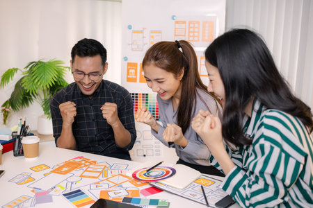 UX/UI designers collaborating during a creative workshop to test interface ideas and exchange feedback for app development, emphasizing teamwork and innovative design thinking.の写真素材