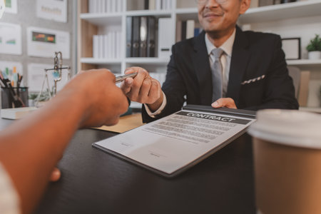 A professional lawyer discussing legal matters with a client in an office, providing legal advice and document review services, symbolizing justice, trust, and professional consultation.の写真素材