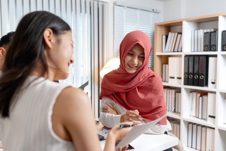 A group of multicultural colleagues in a modern office discussing data and marketing reports. The team focuses on analyzing performance charts and planning strategies for business growth.の写真素材